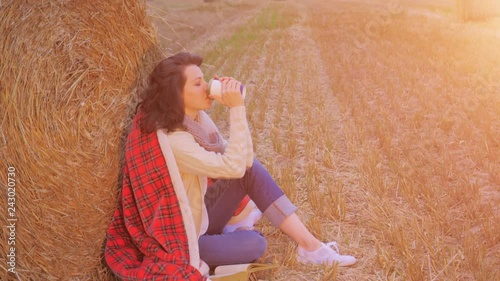 Woman near haystak drinking coffee photo