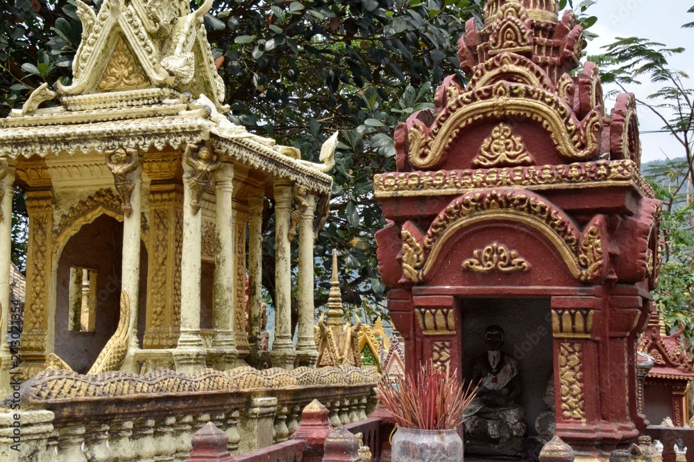THAILAND, BANGKOK - 28 MARCH 2016 - a cluster of spirit houses sit adjacent to a roadside temple dedicated to travellers