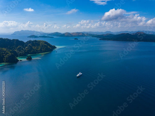 Aerial view to sea with blue water, islands and ship near Coron island. Palawan, Philippines.