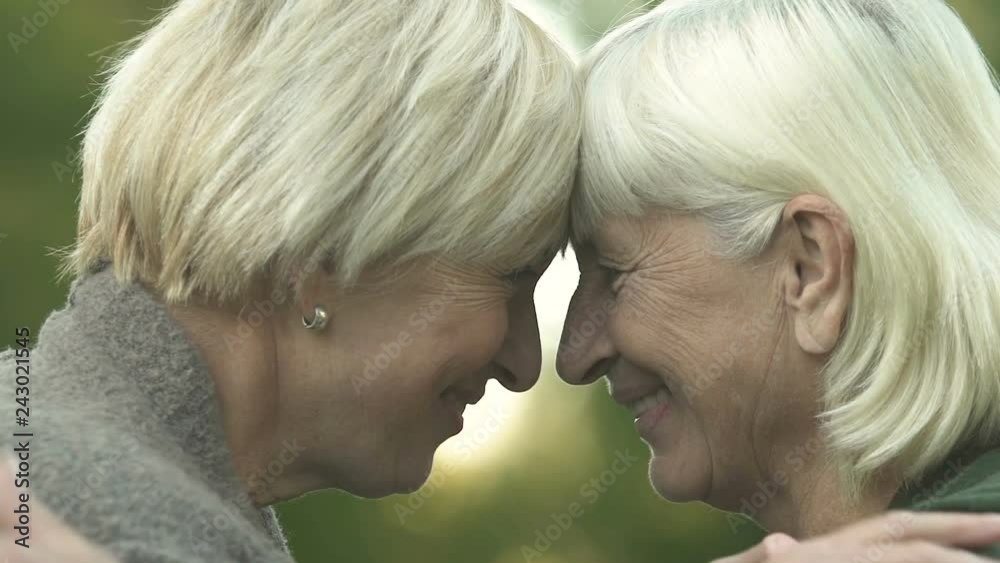 Mature mother and daughter touching heads, family relations, love and support Mature mother and daughter touching heads, family relations, love and support