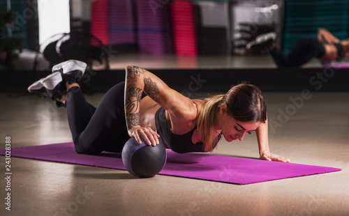 Muscular woman doing push up on medicine ball in gym. Strong female doing exercise in health club.