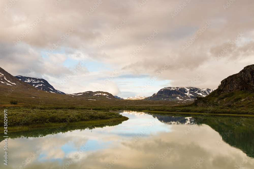 Reflection in a lake of mountains during sunrise at Alesjaure mountain hut in northern Sweden. 