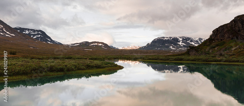 Reflection in a lake of mountains during sunrise at Alesjaure mountain hut in northern Sweden. 