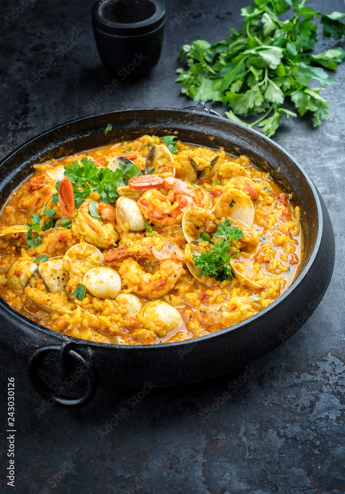 Traditional Portuguese arroz caldoso con almejas with shrimps and calm as top view in a cast-iron pot