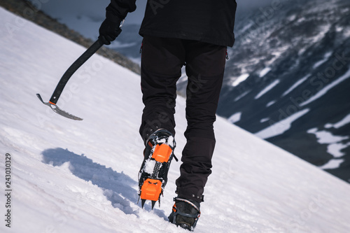 Person climbing a glacier with an ice axe in one hand and crampons.  photo