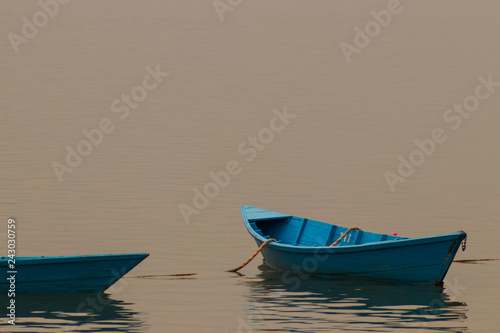 Blue wooden boat in the lake in Pokhara, Nepal an early morning. 
