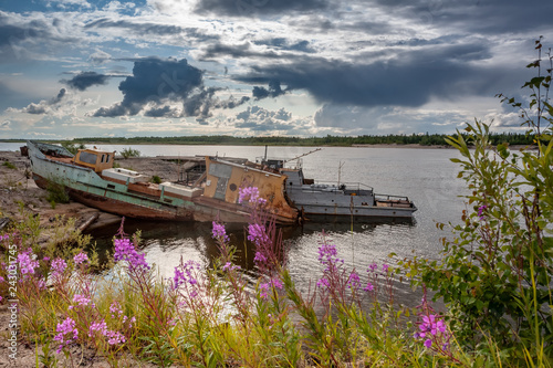 The bank of the Pur River in the rays of the evening sun. Old boats pulled ashore.
