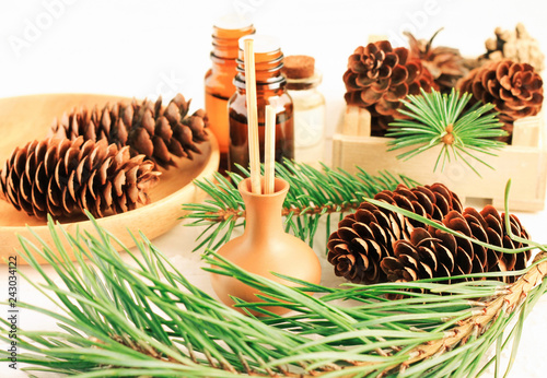 Pine tree aromatherapy, green needles boughs, cones, aromalamp with sticks on table with natural branches, winter scents. photo