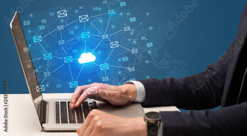 Businessman hand sending a bunch of messages on laptop with cloud computing concept 