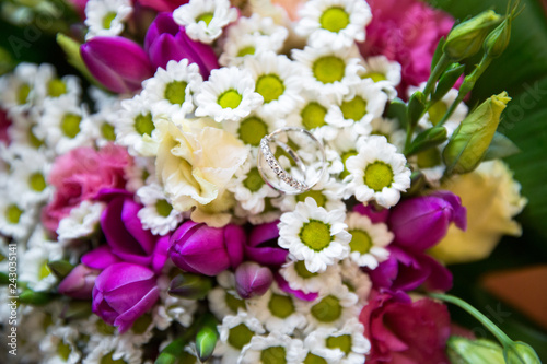 A pair of wedding rings on a bouquet of colorful flowers  close up shot