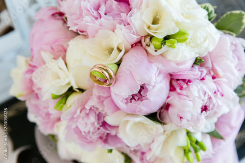 A pair of wedding gold rings on a bouquet of colorful flowers, close up shot © FrameSculptor