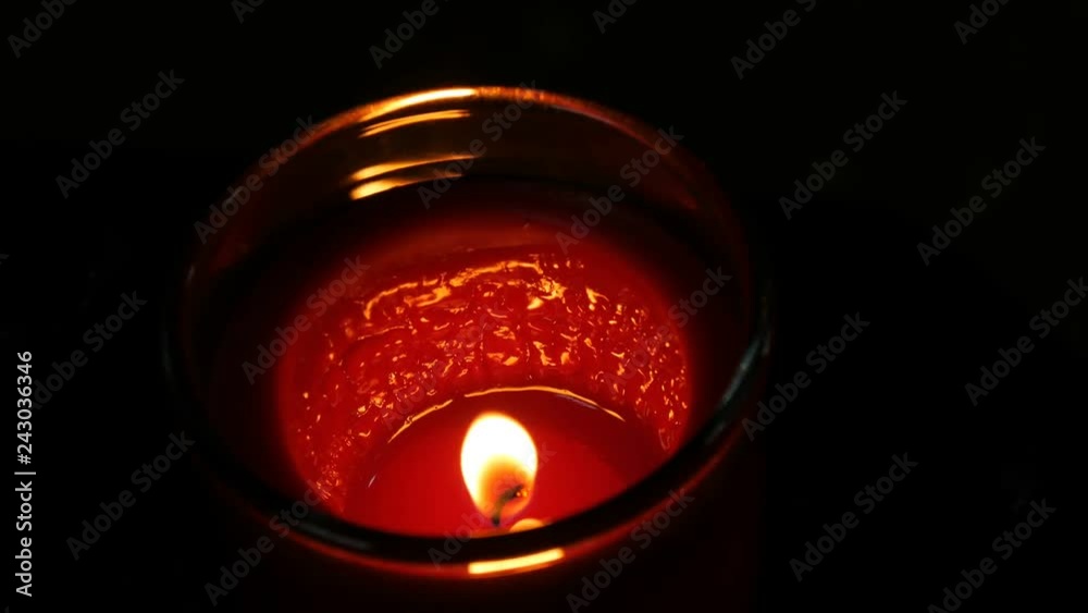 Large round red memorial candle burns in the dark. Flame of a candle on a black background Large round red memorial candle burns in the dark. Flame of a candle on a black background