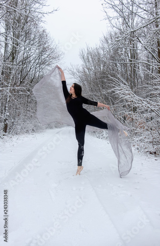 Junge schöne Frau Mädchen Ballett präsentiert sich thatralisch im schwarzem Ballett Anzug im verschneiten Winter Wald  und tanzt auf Zehen Spitze