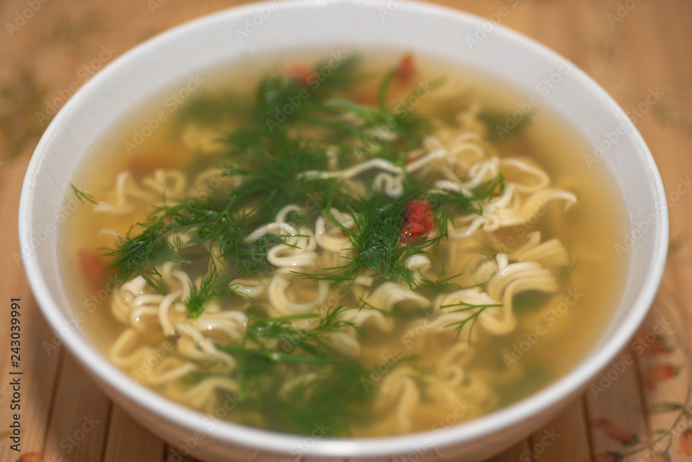 Ramen Noodles soup with dill in white bowl. Close up and top view.