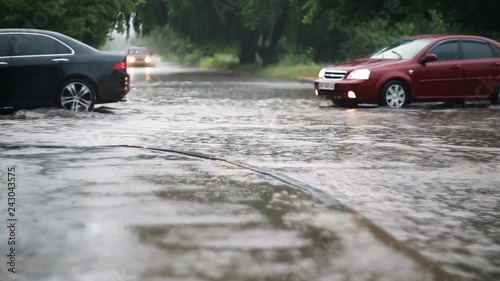 Car traffic on the flooded city street during heavy rain, heavy rainfall. Disaster flood, deluge. Water flow 