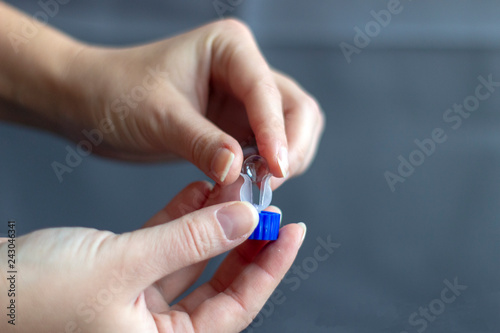 Hands putting orthokeratology lens into container 