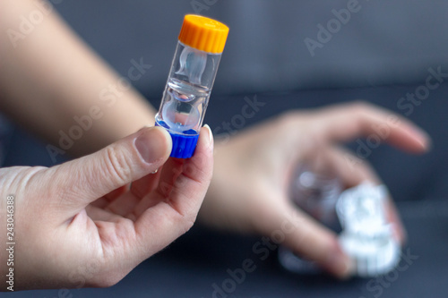 Hand holding night lenses in trael container 