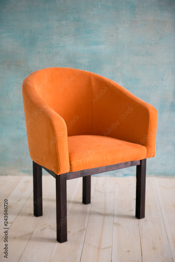 Orange armchair against the background of the blue wall. Interior Orange armchair against the background of the blue wall. Interior