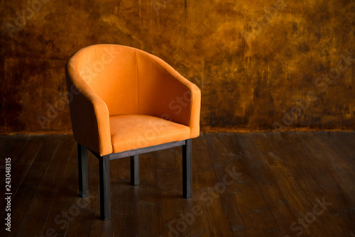 Orange armchair against the background of a brown wall. Interior