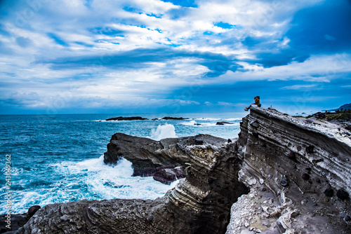 couple seating on the cliff looking over the sea chatting photo