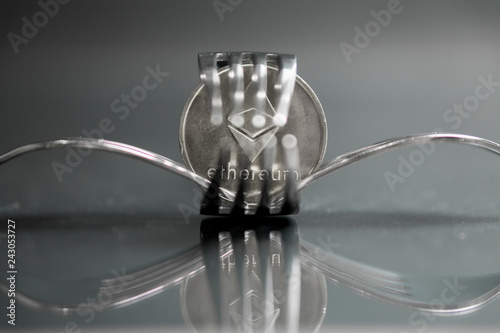 Ethereum cryptocurreny coin placed between forks with reflection, hard fork photo