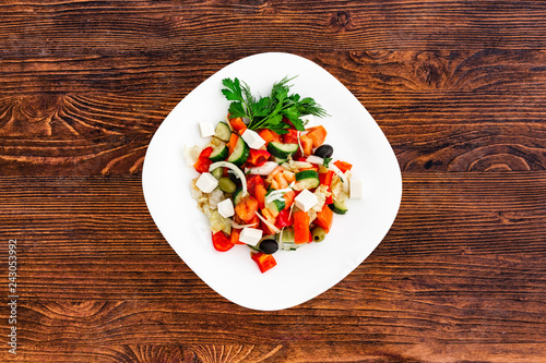 Greek salad of fresh cucumber, tomato, sweet pepper, lettuce, red onion, feta cheese and olives with olive oil. Healthy food, top view