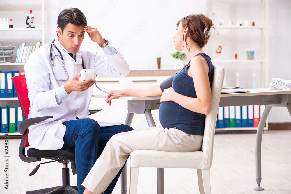 Young doctor checking pregnant woman's blood pressure Young doctor checking pregnant woman's blood pressure