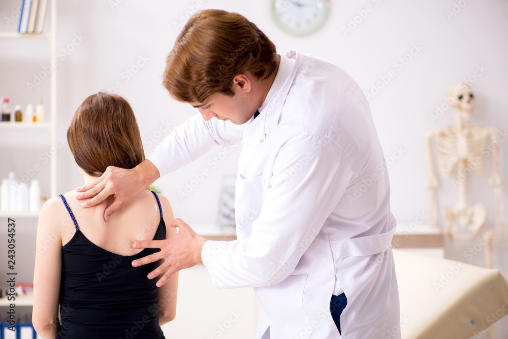 Obraz premium Female patient visiting young handsome doctor chiropractor 