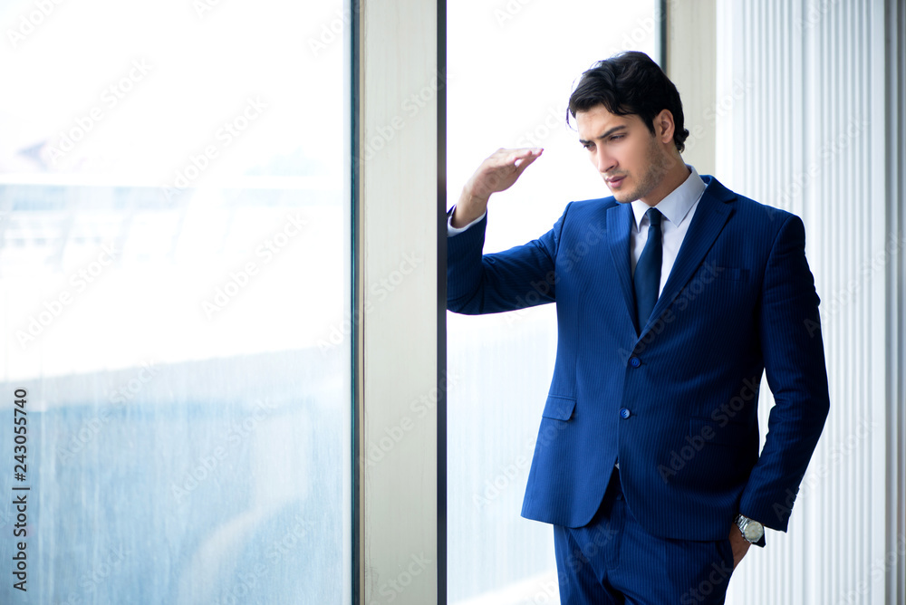 Young handsome businessman standing at the window Young handsome businessman standing at the window