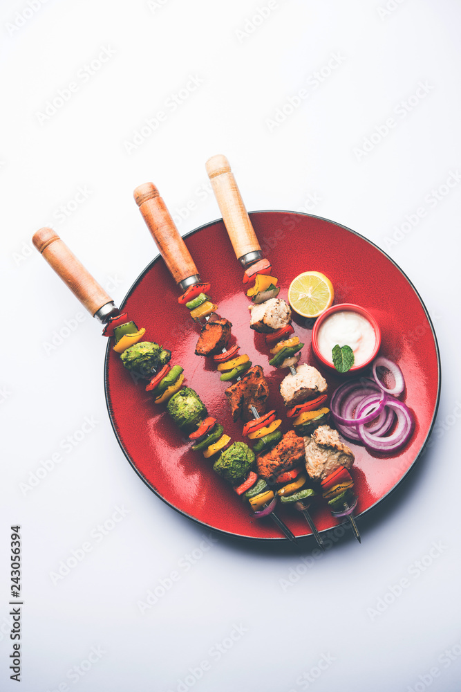 Chicken Hariyali kakab or Malai malai kebab served with skewers and yogurt dip in a plate. selective focus