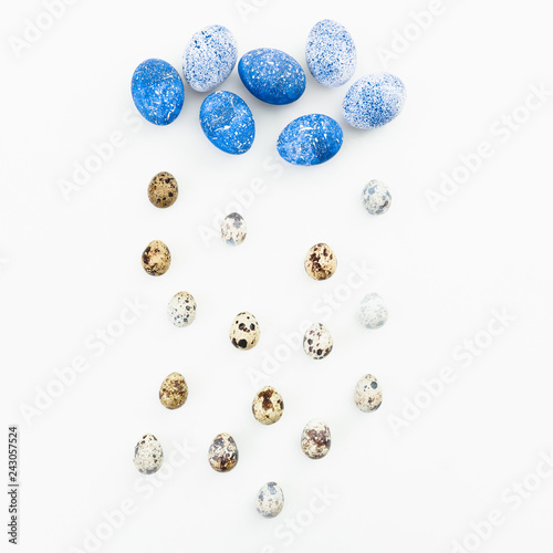 Blue Easter eggs with quail eggs on white background. Flat lay. Top view. Cloud and rain made of easter eggs, creative concept