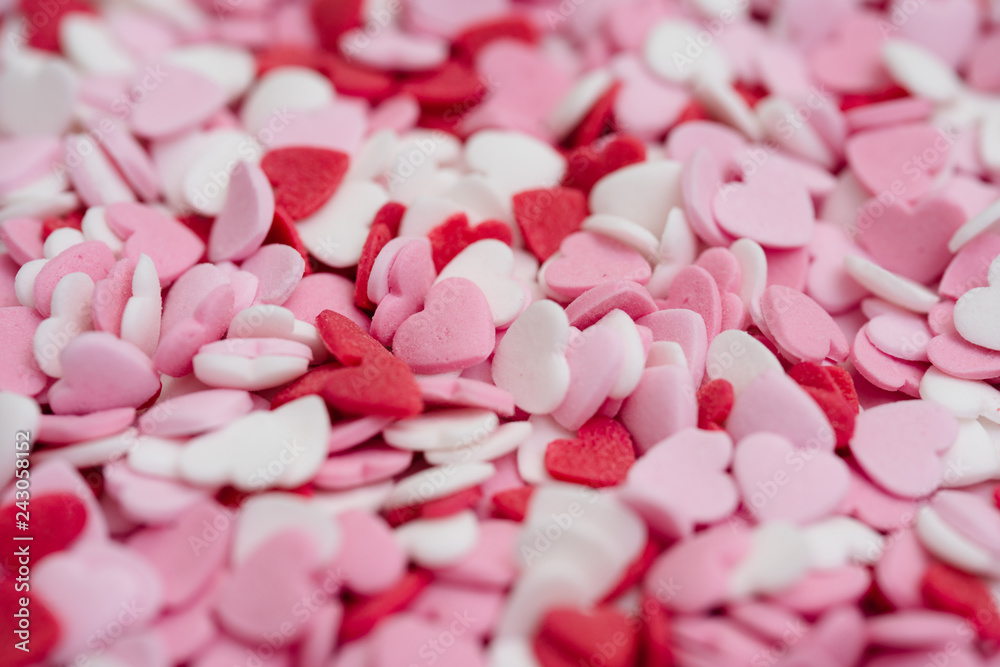 Close up flatlay shot of hundreds of small heart-shaped sugar sprinkles in red, pink and white for Valentine's day card, symbol for love, emotion or romantic feelings as background or wallpaper image
