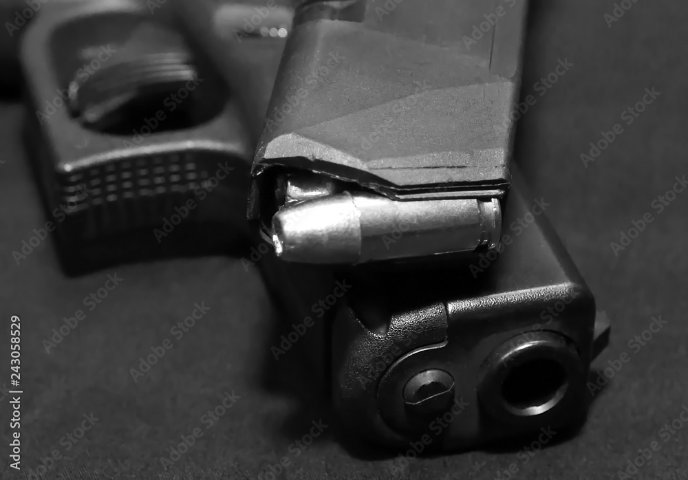 A pistol magazine loaded with 9mm bullets on top of a black 9mm semiautomatic pistol on a black background