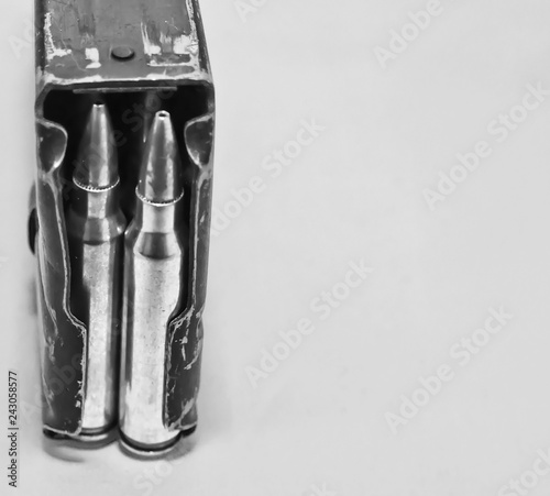 A AR-15 rifle magazine loaded with .223 caliber rifle bullets on a gray background with copy space. Shown in black and white photo