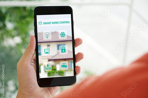 Hand holding smart phone with smart home control icon on screen device, smart home control concept