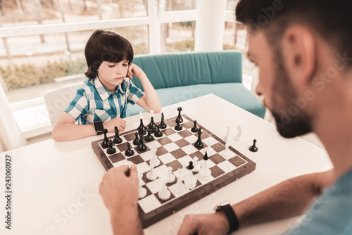 Bearded Father and Son Playing Chess on Table.