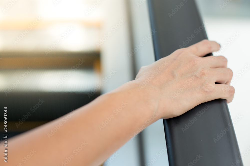 woman's hand is holding the rail of the escalator