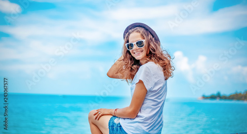 summer portrait of young sexy pretty woman, wearing simple casual trendy white t-shirt and shorts  and bright sunglasses, smiling having fun on vacation in tropical country photo