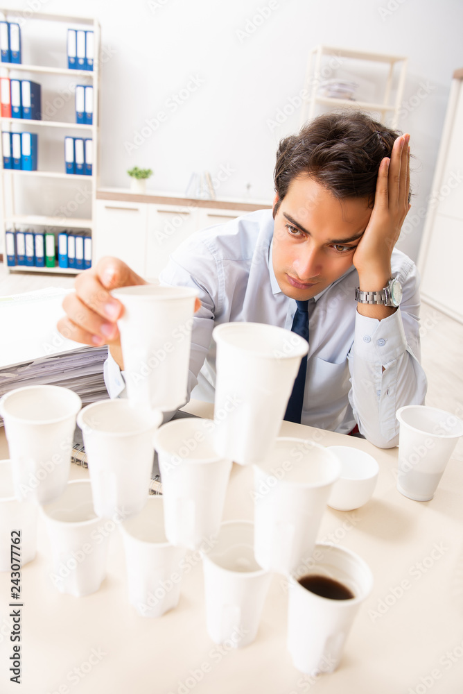 Young employee building pyramid from plastic cups Young employee building pyramid from plastic cups