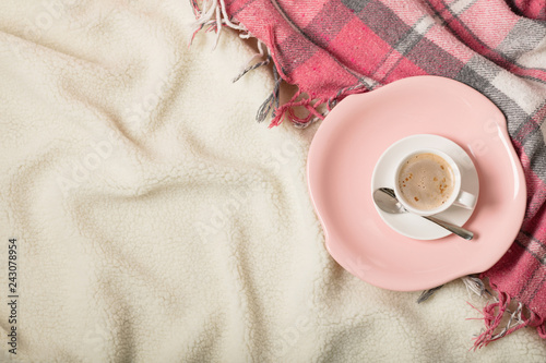 Winter time. A cozy warm pink blanket and a cup of coffee and croissants on the bed.