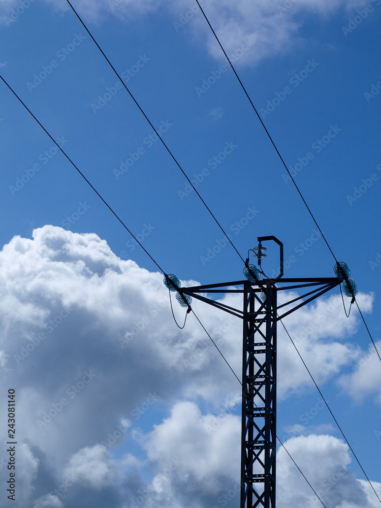 Poste de tendido eléctrico sobre un cielo azul con nubes Poste de tendido eléctrico sobre un cielo azul con nubes
