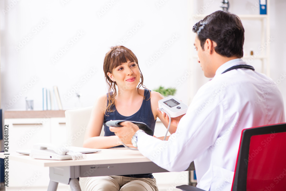Young doctor checking woman's blood pressure Young doctor checking woman's blood pressure