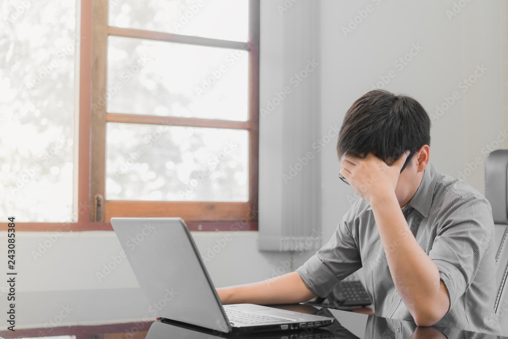 Businessman having stress with laptop computer working in the office,Exhausted asian man touching his head, he is having a bad headache, stress and overwork concept. Businessman having stress with laptop computer working in the office,Exhausted asian man touching his head, he is having a bad headache, stress and overwork concept.