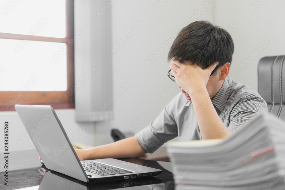 Businessman having stress with laptop computer working in the office,Exhausted asian man touching his head, he is having a bad headache, stress and overwork concept. Businessman having stress with laptop computer working in the office,Exhausted asian man touching his head, he is having a bad headache, stress and overwork concept.
