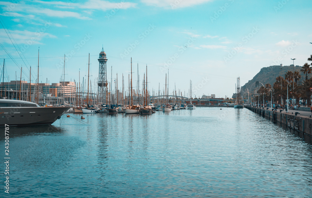 Port of Barcelona, Spain. Yachts, sailing boats and old big tower. Teal and orange view