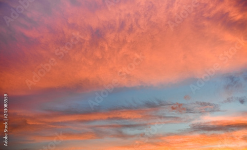 Orange and pink clouds during sunset on blue sky, background