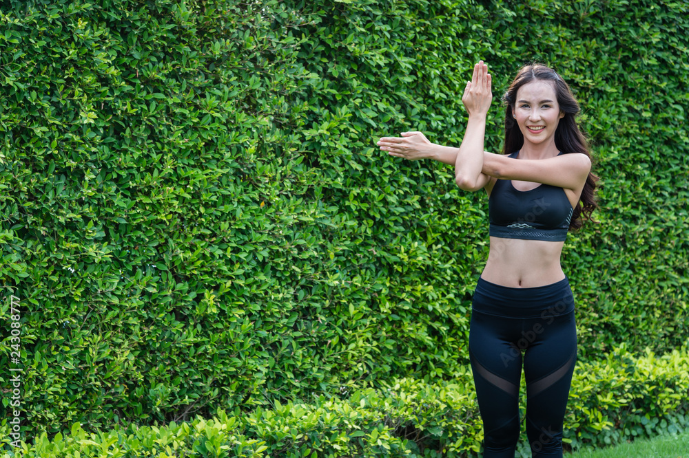 Asian sports women standing and doing exercise by stretching on the grass in the park Asian sports women standing and doing exercise by stretching on the grass in the park