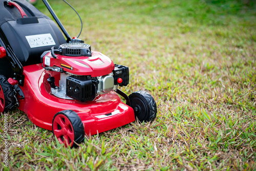 close up lawn mower in the park on the grass. over light [blur and select focus background