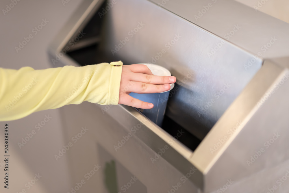 Closeup hand throwing empty paper disposable coffee cup in recycling bin. Recycling, eco friendly approach concept.