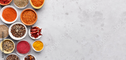 Spices and condiments in bowls on grey background